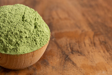 A Bowl of Green Kale Powder on a Wood Counter Top
