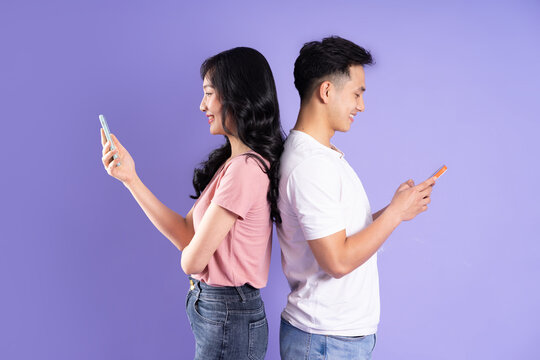 image of asian couple holding smartphone, isolated on purple background