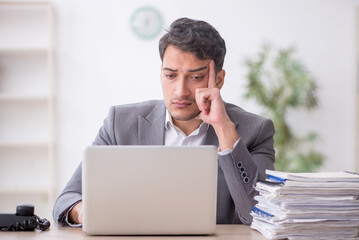 Young male employee and too much work in the office