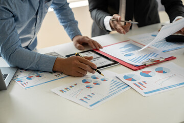 Group of businessmen, investors brainstorming and discussing figures in company financial papers. Financial analyst pointing to data graph to check account meeting concept.