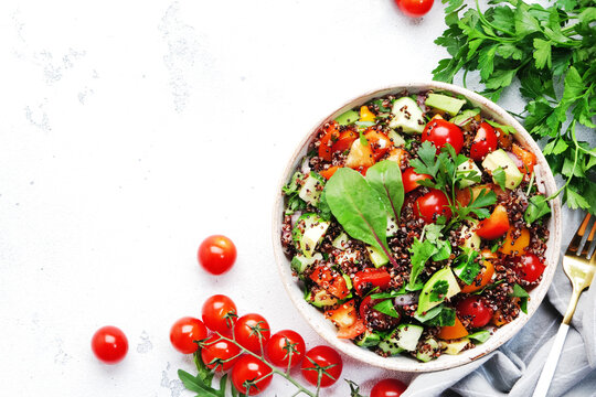 Quinoa tabbouleh salad with red cherry tomatoes, orange paprika, avocado, cucumbers and parsley. Traditional Middle Eastern and Arabic dish. White table background, top view