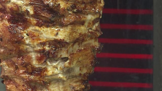 Meat on a spit . Cooking doner kebab or shawarma on a rotating vertical spit. Traditional street fast food