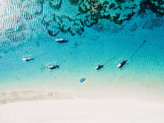 Fishing boats in transparent ocean and white sand beach on paradise island. Aerial view.