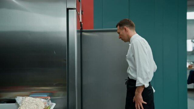 professional kitchen chef looks into the fridge and chooses ingredients for cooking food concept