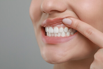 Woman showing healthy gums on grey background, closeup. Space for text
