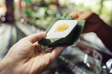 Hands holding Thai coconut sweets Use of natural banana leaves as packaging material, environment and sustainability concept.