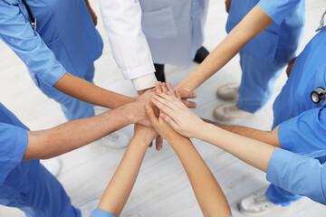Obraz premium Doctor and interns stacking hands together indoors, closeup