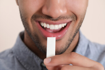 Naklejka premium Man with chewing gum on blurred background, closeup