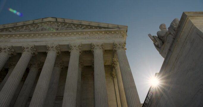 U.S. Supreme Court In Washington D.C. With Statue And Early Morning Sun Appearing Over Building