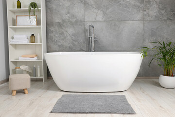 Naklejka na ściany i meble Stylish bathroom interior with ceramic tub, care products and towels in cabinet
