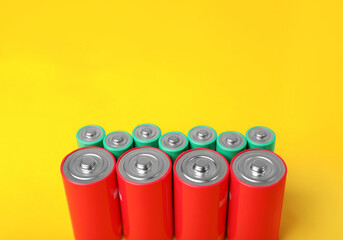 Batteries of different sizes on yellow background. Space for text