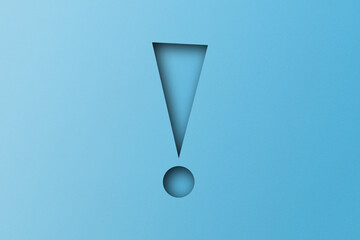Light blue paper punched into the shape of an exclamation mark. warning sign Set on a light blue paper background.