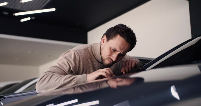 A man examines a car for defects, found scratch