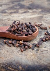 Closeup of Dry Cloves in a Wooden Spoon Isolated on Wooden Background