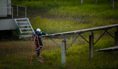 Fototapeta na wymiar An electrical engineer is inspecting a solar cell that has been used for some time, installed on a field hundred acres of grass.