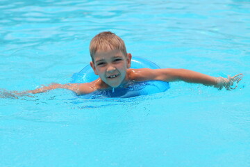 Fototapeta na wymiar Happy boy with inflatable ring in swimming pool, space for text. Summer vacation