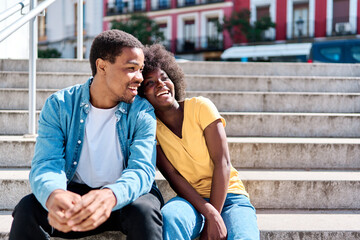 African couple sitting together on stairs in the street