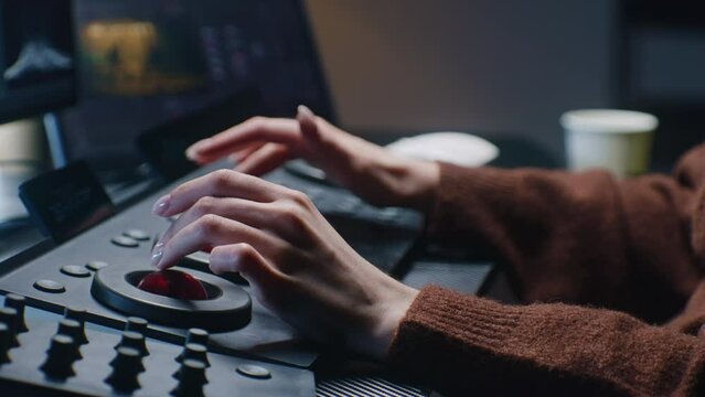 The editor uses digital color grading control panel. Colorist makes video or photo color correction on computer in studio. Tablet with footage and program interface with RGB color wheels at background