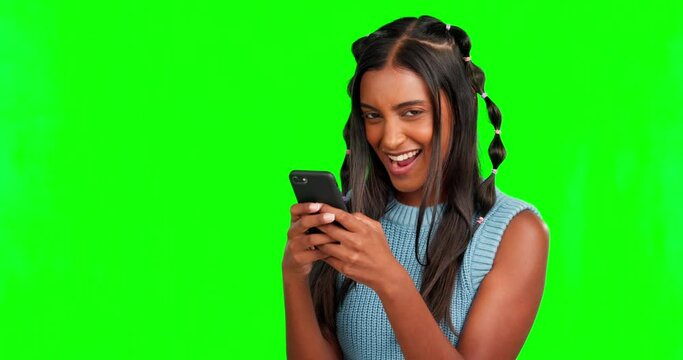 Phone, gossip or surprise with a woman on a green screen background in studio browsing social media. Mobile, contact and news with an attractive young female typing a text message on chromakey mockup