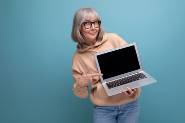 middle aged woman freelancer with gray hair studying remote profession holding laptop in hands on studio background with copy space