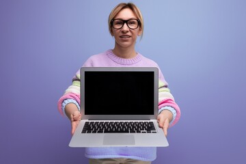 nice blond woman freelancer with a laptop in her hands shows a screen mockup on a purple background
