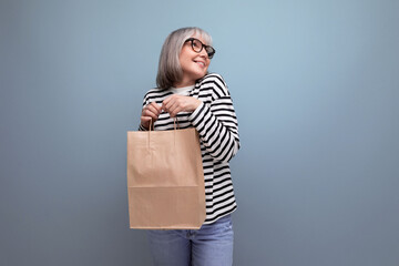 adorable middle aged woman holding craft packaging for shopping on bright background with copy space