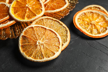 Dry orange slices on black table, closeup