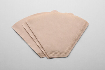 Paper coffee filters on light grey background, flat lay
