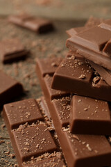 Pieces of tasty chocolate on wooden table, closeup