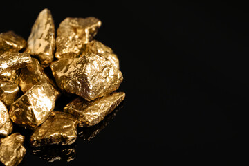 Pile of shiny gold nuggets on black background, closeup. Space for text