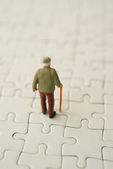 miniature figurine of an elder man with a walking stick on a jigsaw puzzle 
