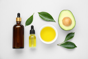 Essential oil, fresh cut avocado and leaves on white background, flat lay