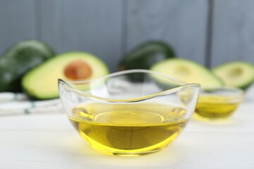 Bowl with avocado oil on white table, closeup