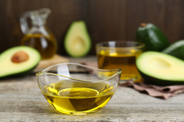 Bowl with avocado oil on wooden table, closeup
