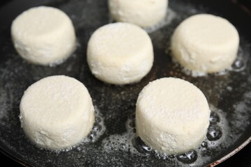 Fototapeta na wymiar Uncooked cottage cheese pancakes in frying pan, closeup