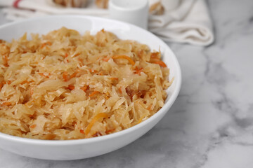 Bowl with tasty sauerkraut on white marble table, closeup. Space for text