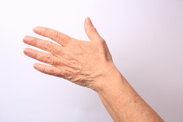 Closeup view of older woman's hand on white background