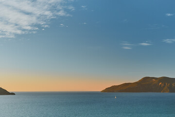 Magnificent sunset on the Aegean Sea with islands and a sailboat. Seascape, travel and yachting, idea for background or advertising of sea voyages