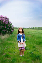 beautiful young girl with a bouquet of lilacs, a girl in lilacs, lilacs in spring. Young beautiful brunette girl posing with a bouquet of lilac

