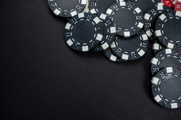 classic colored round poker chips scattered on a black table.