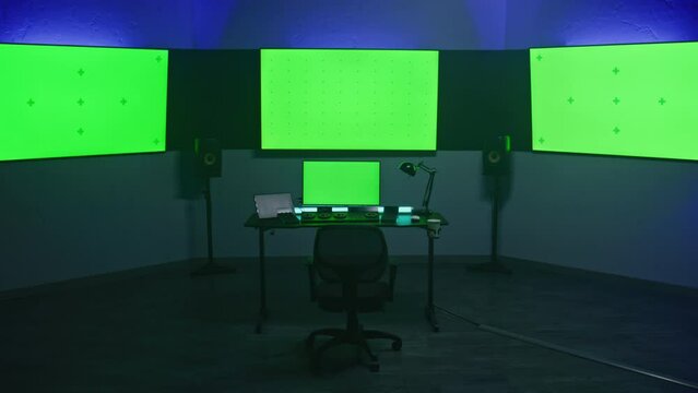 Studio with modern equipment for video color correction. Computer, digital tablet and big screens showing program interface, video footage. Color grading control panel. Post production. Green screen.