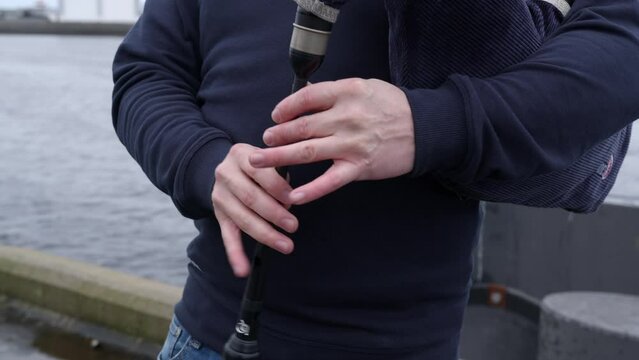 Static shot of a highland bagpipe player's fingers as he plays his bagpipes on a pier. Shot near Stornoway on the Isle of Lewis, part of the Outer Hebrides of Scotland.