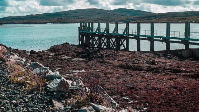 Time lapse of the tide around a pier. Seaweed fills the port in the foreground. Filmed on the Isle of Lewis, part of the Outer Hebrides of Scotland.
