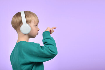 a boy child in headphones shows the direction with a finger
