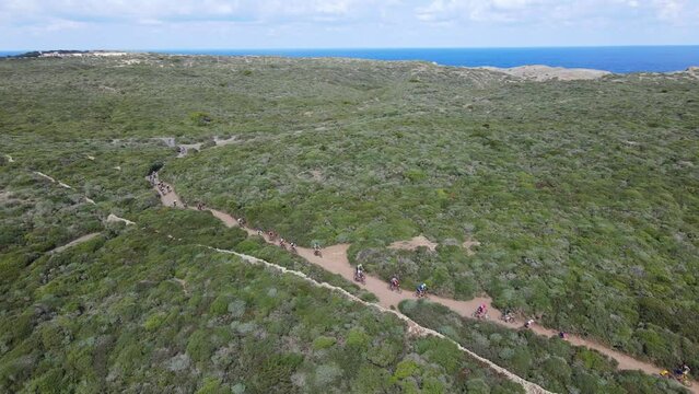 Mountain bike riders following trail along the coast of Menorca in Spain.