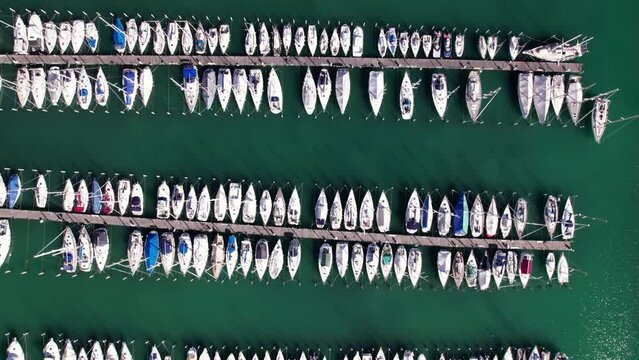 Aerial top down panning of moored white yacht boat in parallel row pier, background
