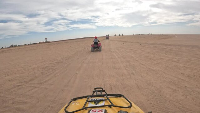 Caravan of quad bikes in deadly sandy desert, POV driving view