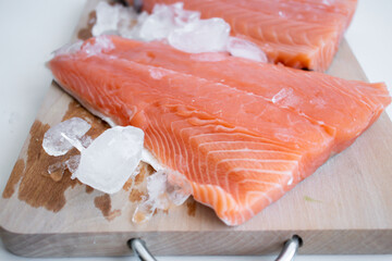 raw salmon fillet on a wooden cutting board. On a white background.