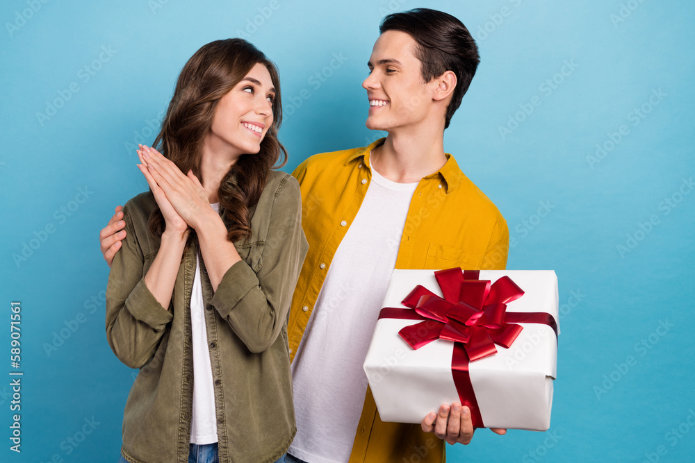 Sticker Photo of pretty cute smile couple hugs look each other hold wrapped present girlfriend with boyfriend marriage day isolated on blue color background