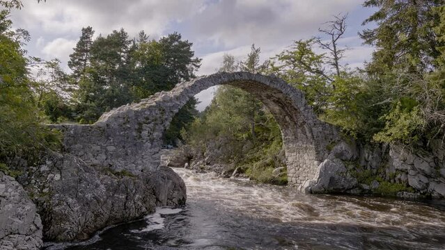 Medieval ancient Stone Packhorse Bridge over the Dulnain river, Carrbridge, Scotland, UK with strong water flow at sunset